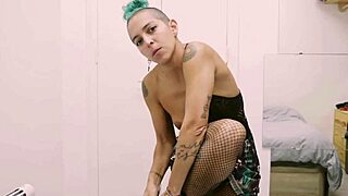 Short tattooed girl with green hair rips off her clothes in an intense striptease