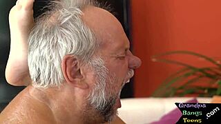 An elderly man slams a young European girl heavily on a bed