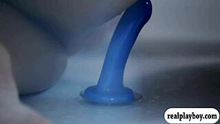 Two glamour babes passionately using a blue dildo